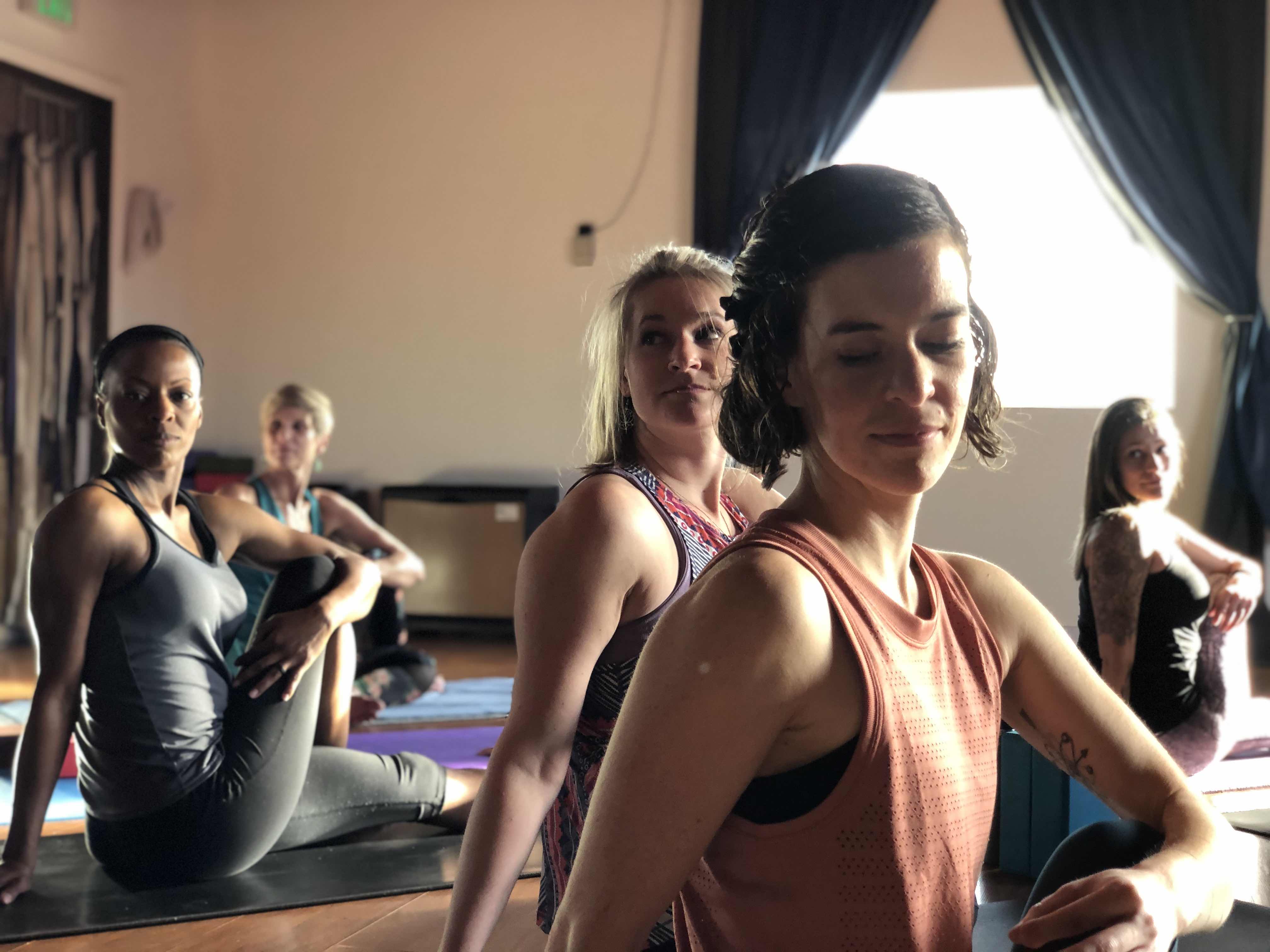 Photo of Erika in Ardha Matsyendrāsana with other students behind her