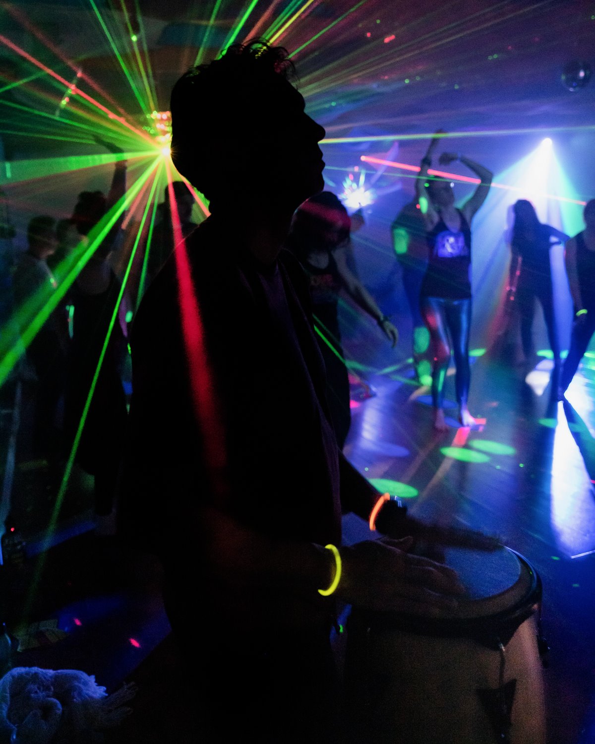 Outline of man palying drums in laser lit room