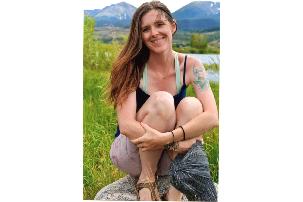 Photo of Alyssa sitting on a rock in the mountains