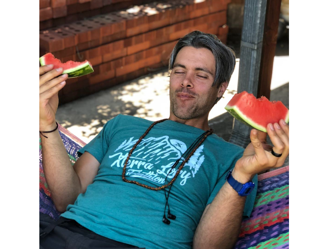 Photo of Austin eating watermelon on a hammock