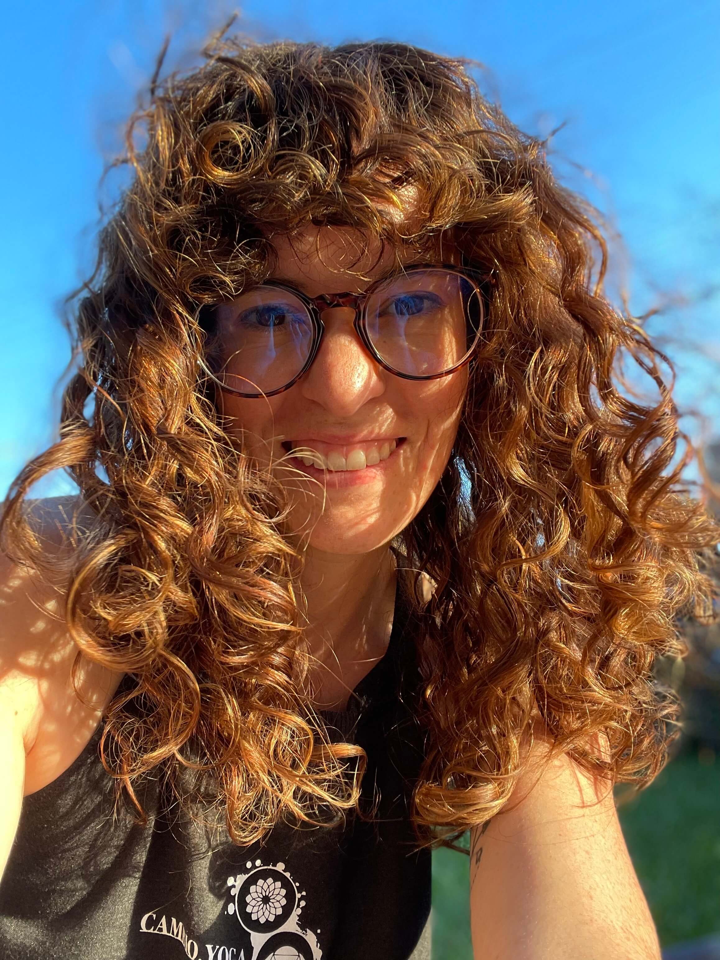 Photo of Erika outside, with her curly hair blowing in her face
