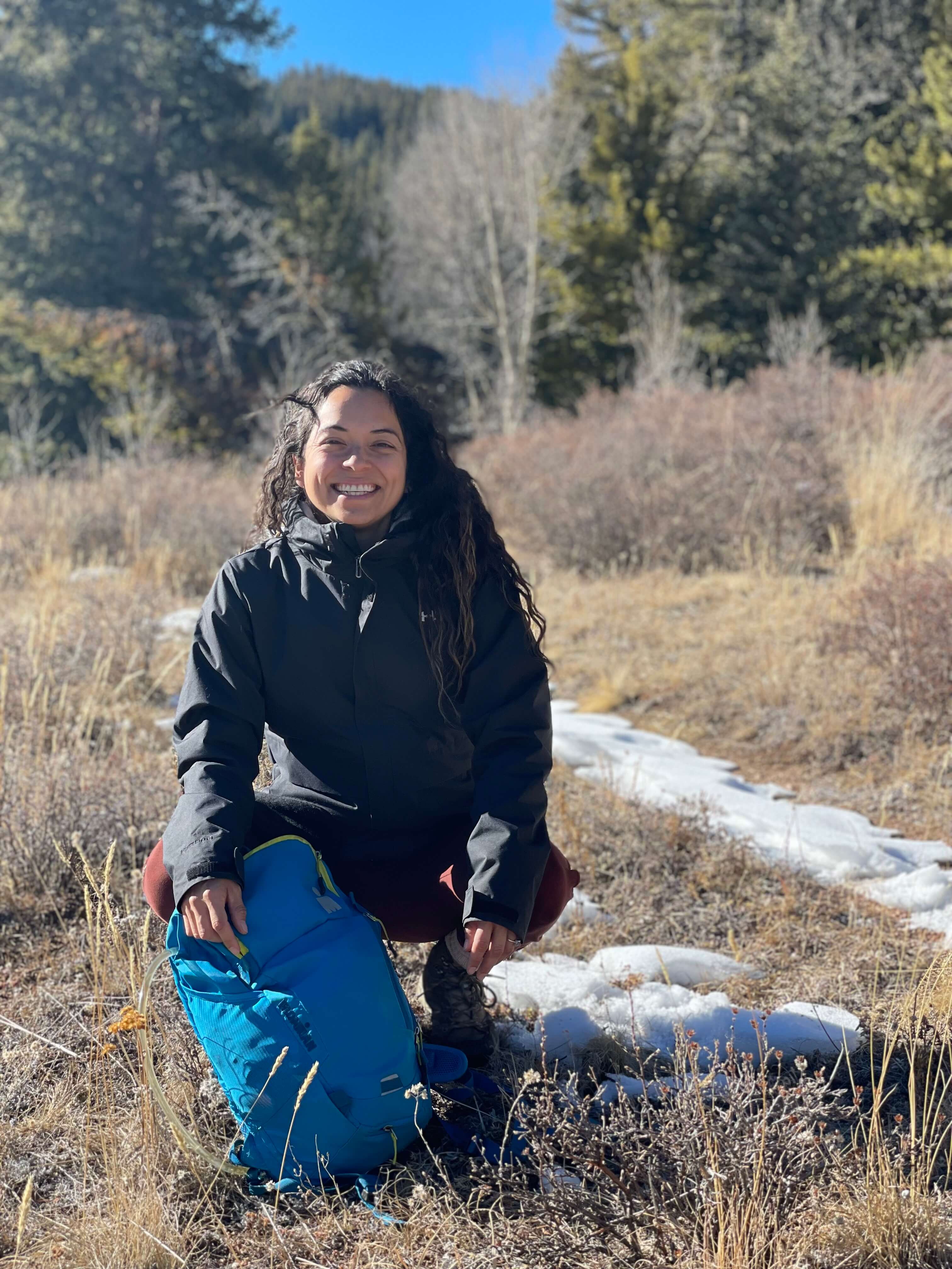 Photo of Jessica outdoors, kneeling down and smiling