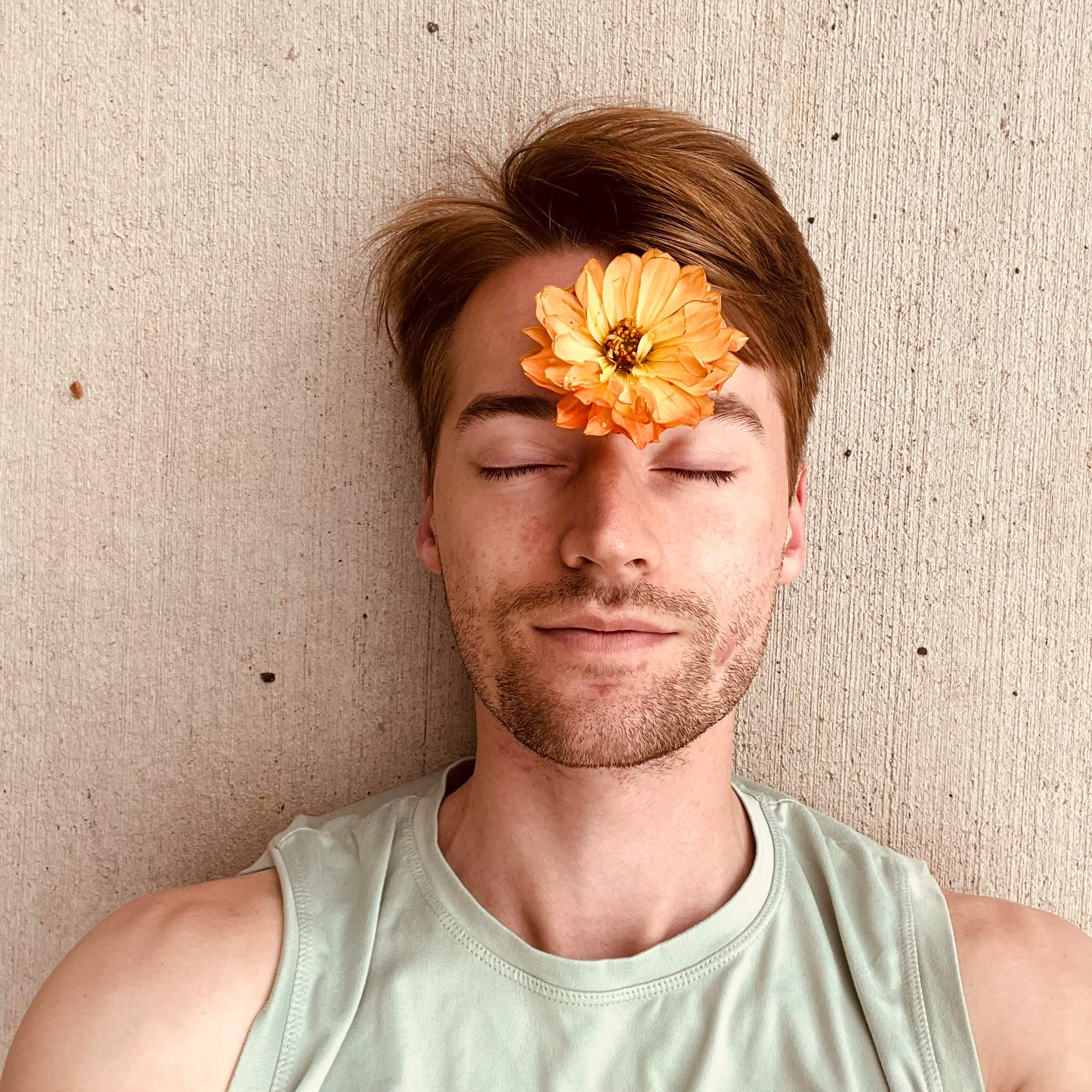 Photo of Caleb laying down with a flower on their forehead
